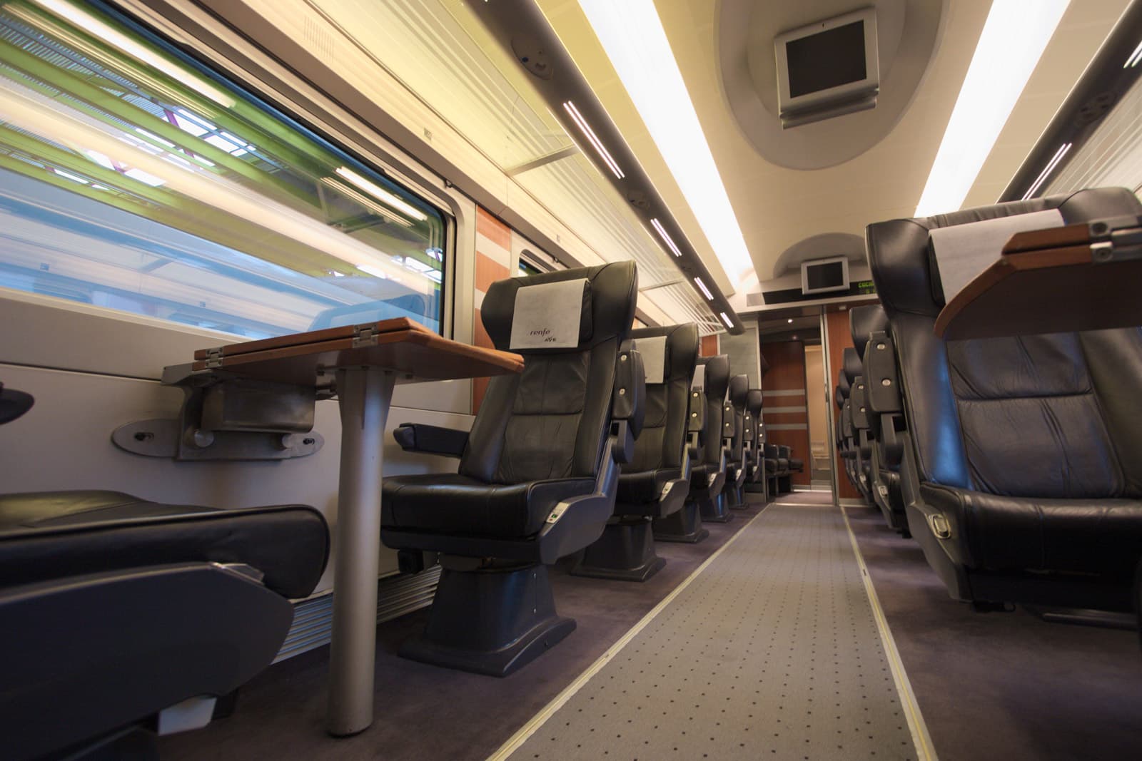 Interior de coche del proyecto 112 de Talgo, con mesitas junto a los asientos.