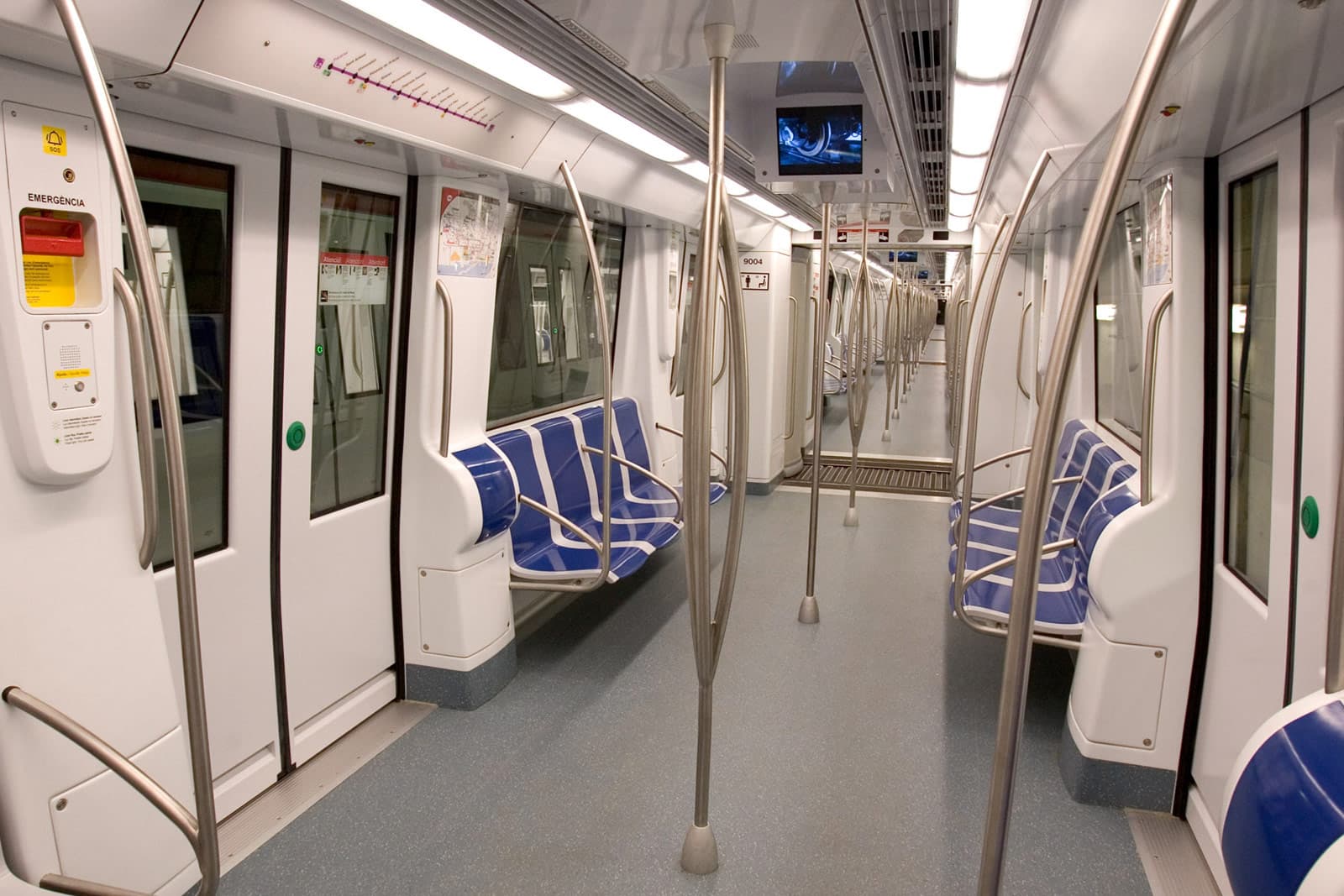 Interior de un vagón renovado de la Línea 1 del Metro de Barcelona, con asientos azules.