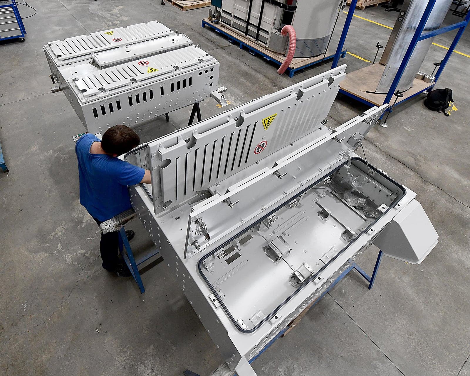 Operario montando un cofre de baja tensión de Alstom en el taller, con las tapas abiertas.